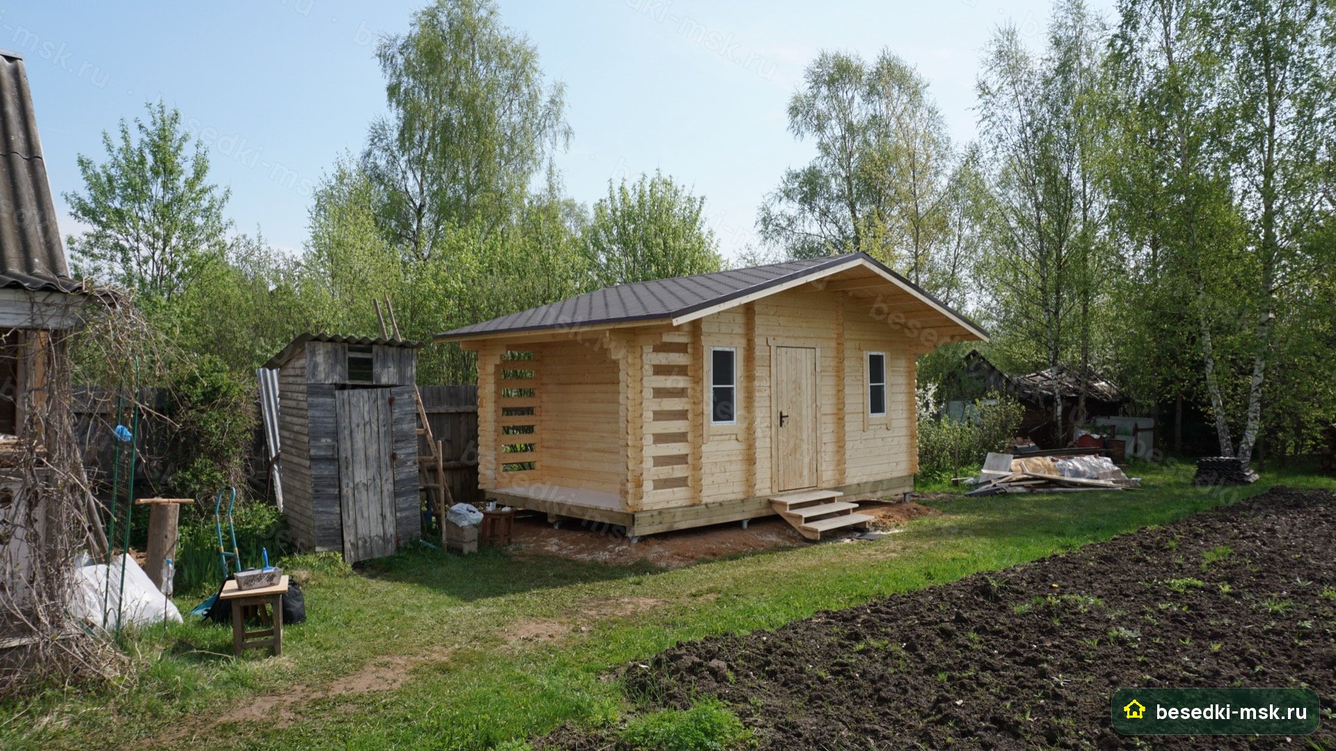 3/4 фронт-лево шире: фасад с дровником-торцом, грядка на переднем плане